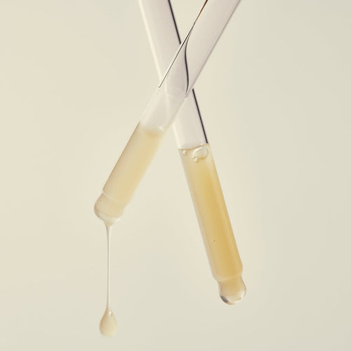 Two droppers of Pro Vitality Face Serum on a light beige background.