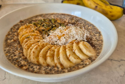 Bowl of chia pudding with sliced bananas and nuts on a light surface.
