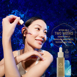 Woman applying Manuka Health Pro Vitality Face Serum skincare product with blue background and text about product benefits. 